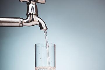 Clean water is poured into a glass from the tap