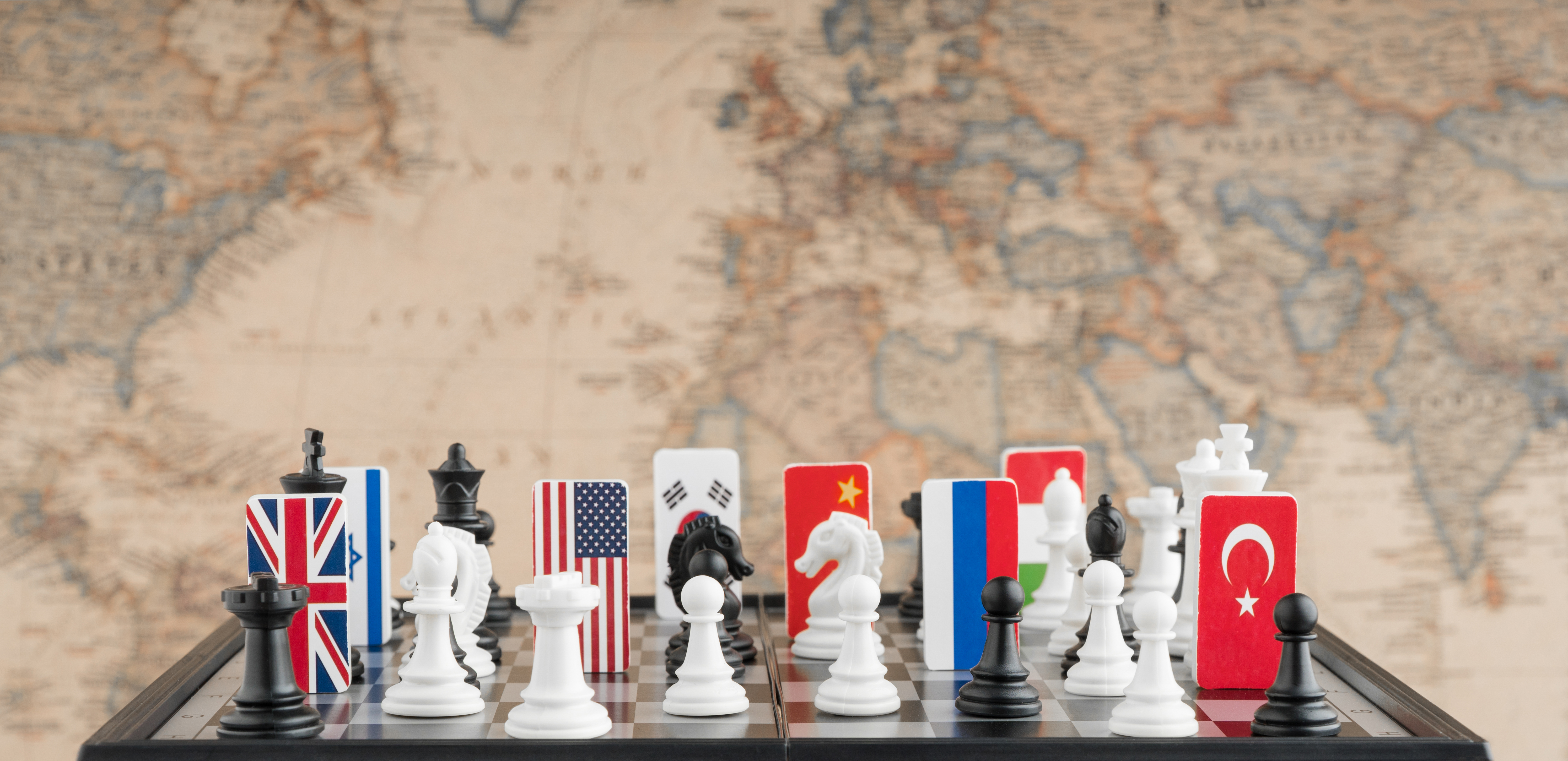 Country flag symbols on the chessboard with figures on the background of the political map of the world. Conceptual photo of a political game.