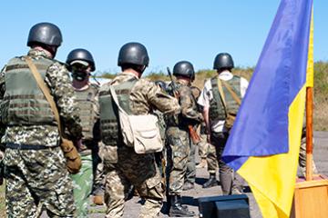 A group of armed Ukrainian soldiers near the flag of Ukraine